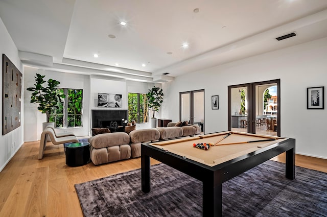 game room featuring a raised ceiling, light hardwood / wood-style flooring, billiards, and french doors