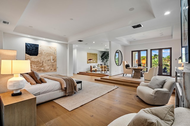 bedroom featuring a raised ceiling, french doors, and light hardwood / wood-style flooring