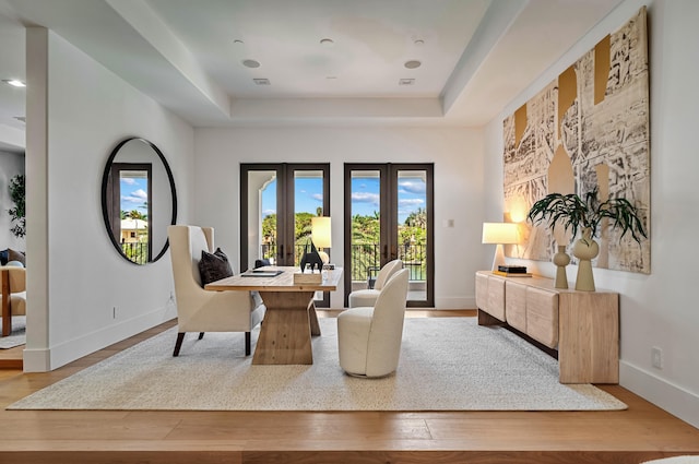 interior space featuring light hardwood / wood-style floors, a raised ceiling, and french doors