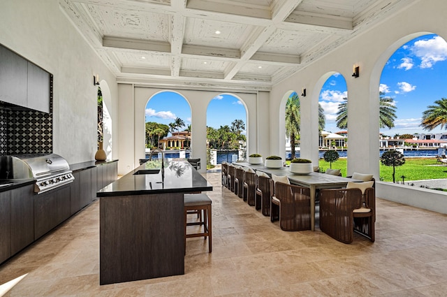 view of patio featuring exterior kitchen, a water view, grilling area, and an outdoor wet bar