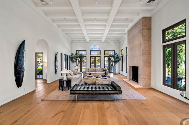 living room with a fireplace, french doors, light wood-type flooring, and beamed ceiling