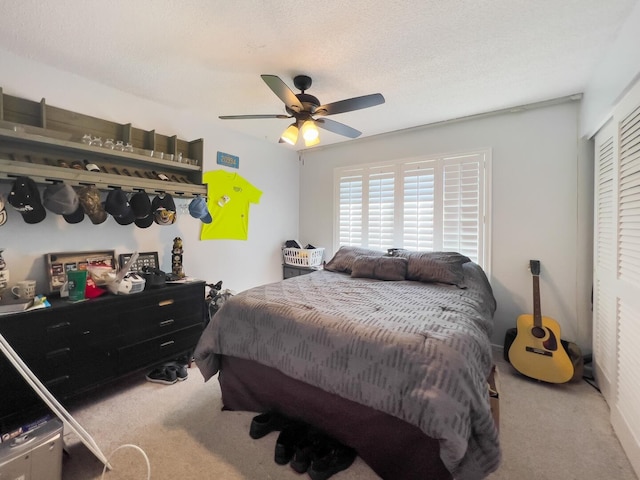 bedroom with a closet, light carpet, ceiling fan, and a textured ceiling