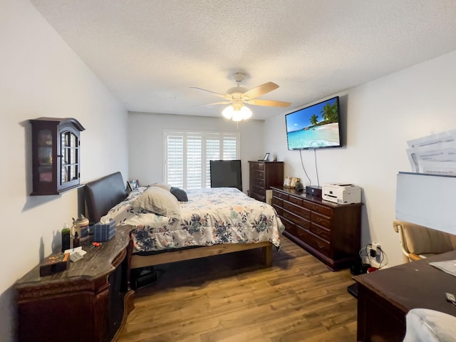 bedroom with dark hardwood / wood-style floors, ceiling fan, and a textured ceiling