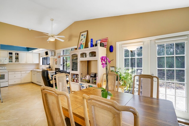 tiled dining space with a healthy amount of sunlight, lofted ceiling, sink, and ceiling fan