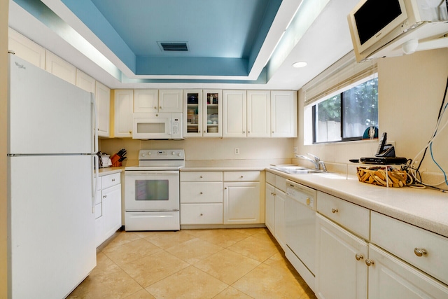 kitchen with white appliances, a raised ceiling, white cabinetry, sink, and light tile floors