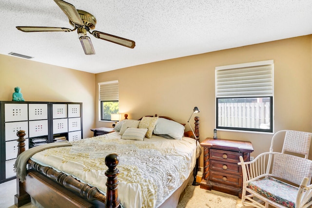 bedroom featuring a textured ceiling, ceiling fan, and light carpet