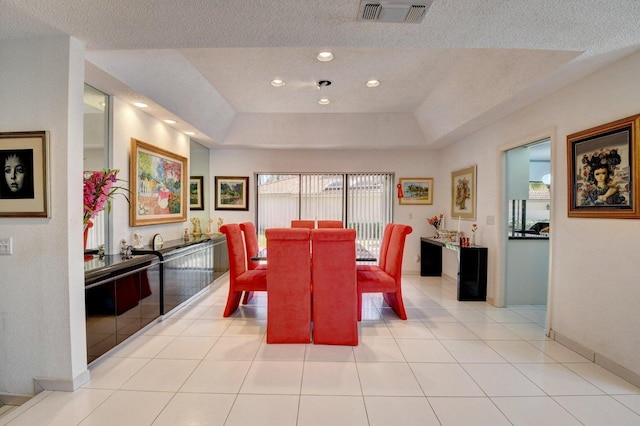 tiled dining room featuring a raised ceiling and a textured ceiling