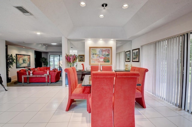 tiled dining room featuring a textured ceiling and a tray ceiling