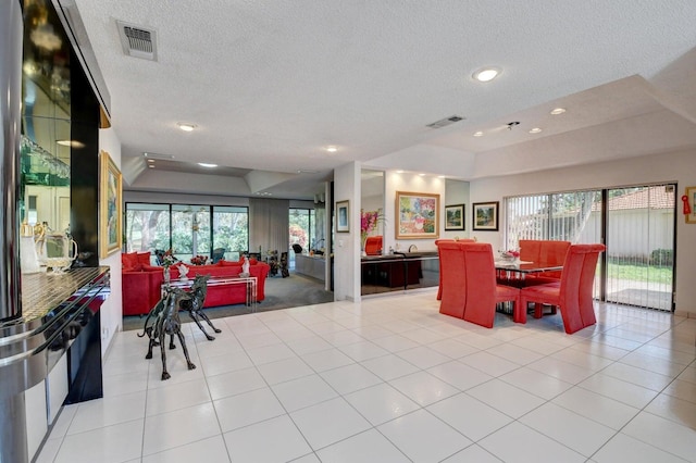 dining area featuring light tile patterned floors, a textured ceiling, and a healthy amount of sunlight