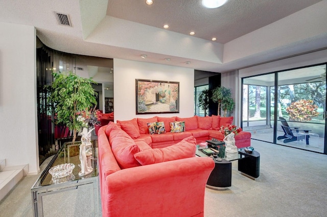 living room with carpet floors, a textured ceiling, and a tray ceiling