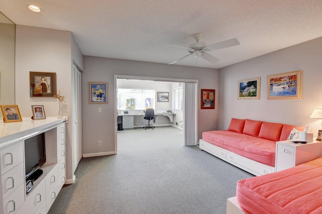 carpeted living room featuring ceiling fan and a textured ceiling