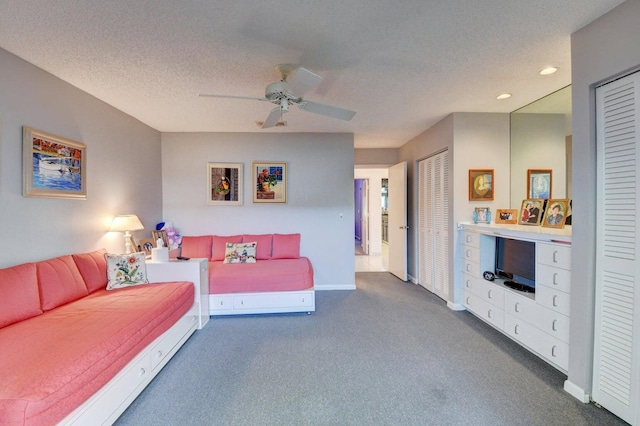 living room with ceiling fan, dark carpet, and a textured ceiling