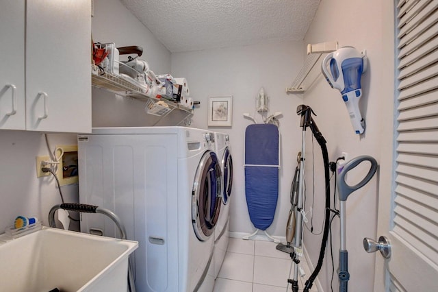 washroom with sink, cabinets, independent washer and dryer, a textured ceiling, and light tile patterned floors