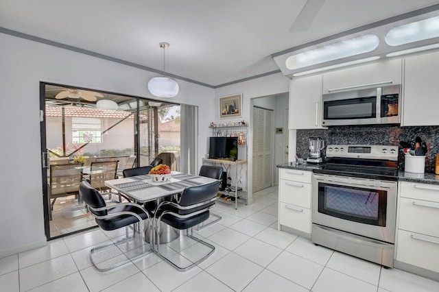 kitchen with hanging light fixtures, appliances with stainless steel finishes, tasteful backsplash, light tile patterned flooring, and white cabinetry