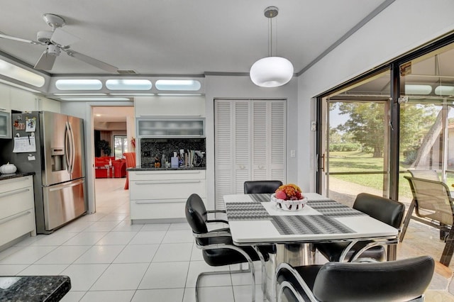 tiled dining space with ceiling fan and ornamental molding