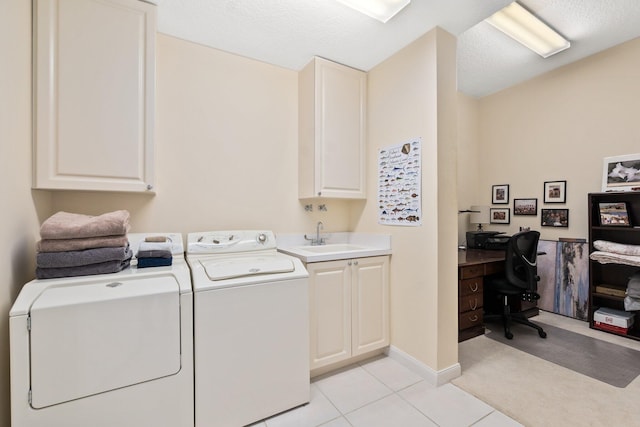 laundry area with sink, washing machine and dryer, cabinets, and light tile floors