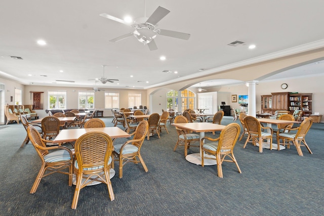 carpeted dining room featuring ornamental molding, ceiling fan, and decorative columns