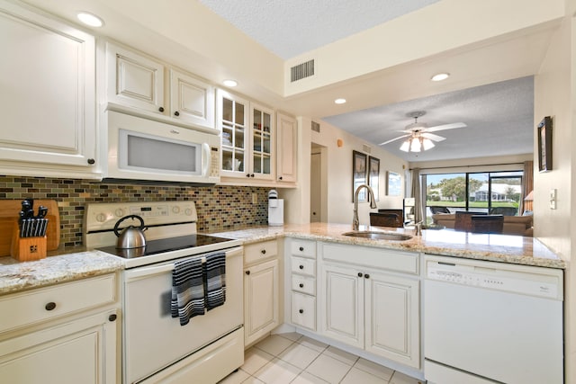 kitchen featuring backsplash, ceiling fan, white appliances, sink, and light stone counters