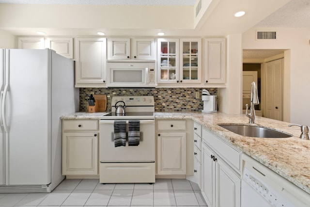 kitchen with white appliances, light tile floors, tasteful backsplash, and light stone counters