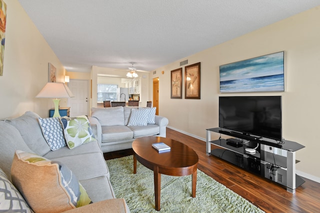 living room featuring a textured ceiling, ceiling fan, and dark hardwood / wood-style flooring