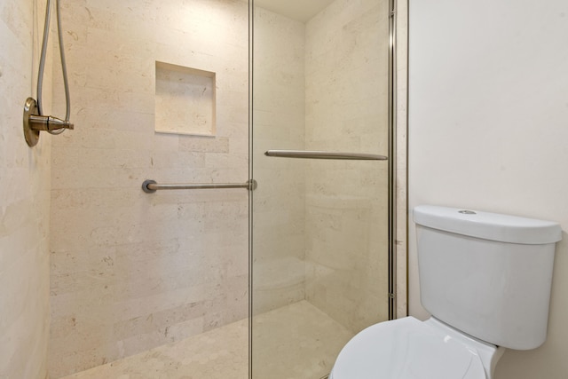 bathroom with toilet and a shower with shower door