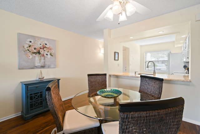 dining space with ceiling fan, a textured ceiling, and dark hardwood / wood-style floors