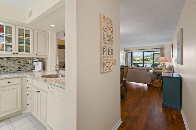 kitchen with white cabinetry, light tile floors, white dishwasher, light stone counters, and tasteful backsplash