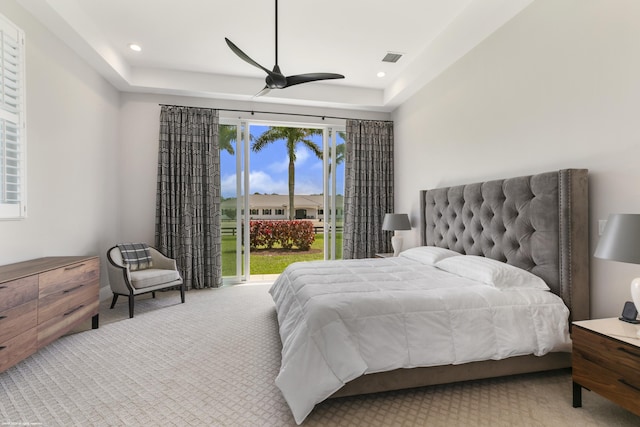 carpeted bedroom with ceiling fan, a raised ceiling, and access to outside