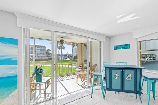 doorway to outside with light tile patterned flooring, a water view, and ceiling fan