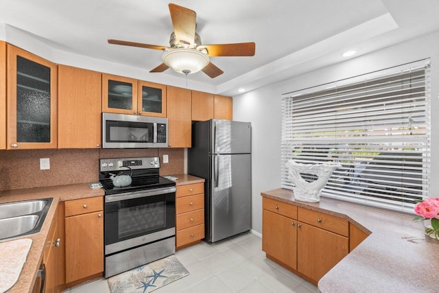 kitchen featuring tasteful backsplash, appliances with stainless steel finishes, sink, light tile patterned flooring, and ceiling fan