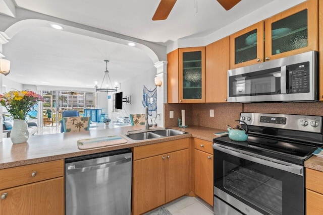 kitchen with tasteful backsplash, sink, ceiling fan with notable chandelier, kitchen peninsula, and stainless steel appliances