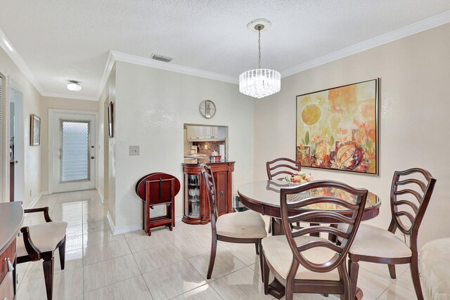 tiled dining space featuring a textured ceiling, crown molding, and a chandelier