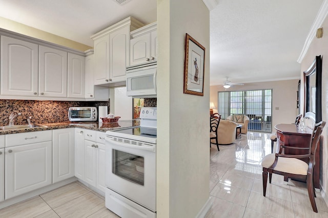 kitchen with white appliances, crown molding, sink, dark stone countertops, and ceiling fan