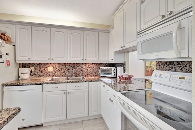 kitchen with dark stone countertops, white appliances, tasteful backsplash, and white cabinetry