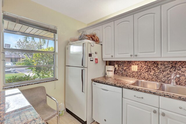 kitchen with sink, white appliances, tasteful backsplash, white cabinetry, and dark stone countertops