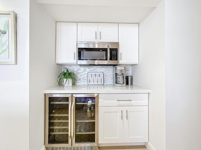 bar featuring tasteful backsplash, white cabinetry, and beverage cooler