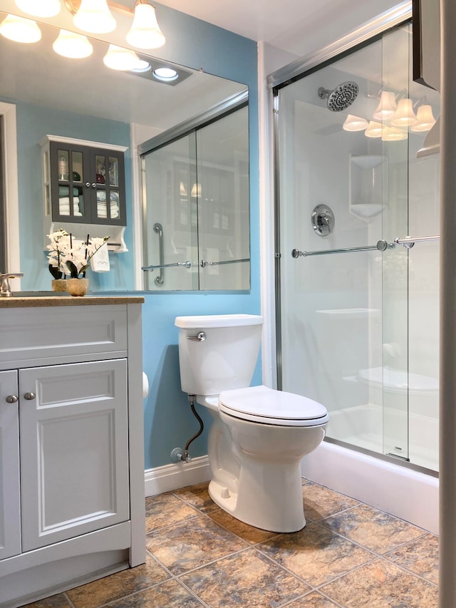 bathroom with a shower with door, tile floors, vanity, and toilet