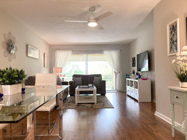 living room with dark hardwood / wood-style flooring, ceiling fan, and a textured ceiling