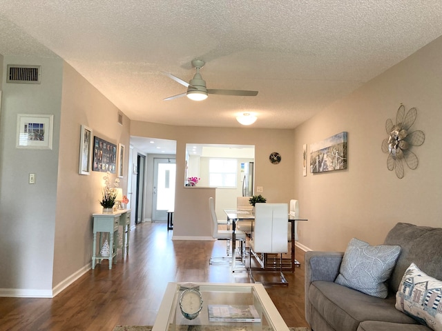 living room featuring ceiling fan, dark hardwood / wood-style floors, and a textured ceiling