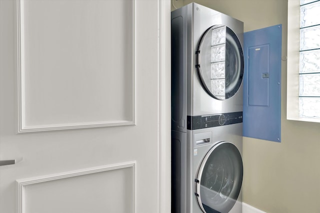 laundry area featuring electric panel, plenty of natural light, and stacked washer / drying machine