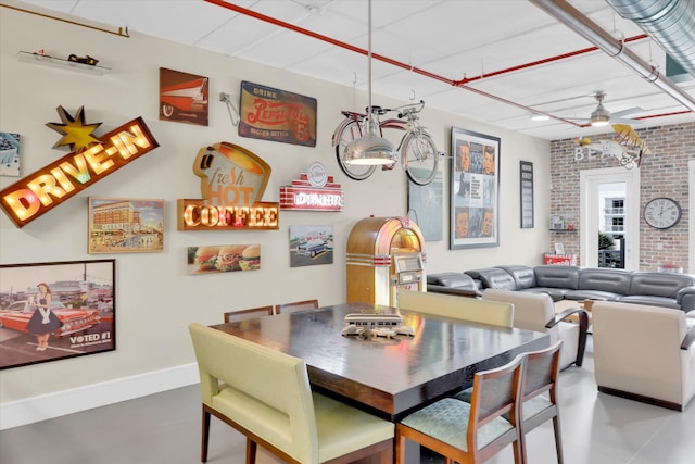 dining area with ceiling fan and brick wall