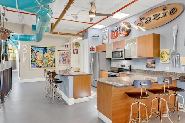 kitchen with a kitchen breakfast bar, kitchen peninsula, stainless steel appliances, and concrete flooring