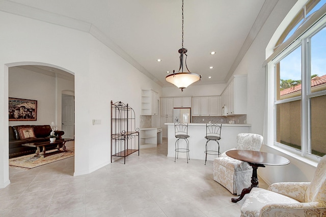 living area with vaulted ceiling, ornamental molding, and light tile floors