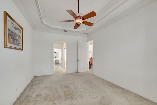 spare room featuring ceiling fan, ornamental molding, a tray ceiling, and light colored carpet