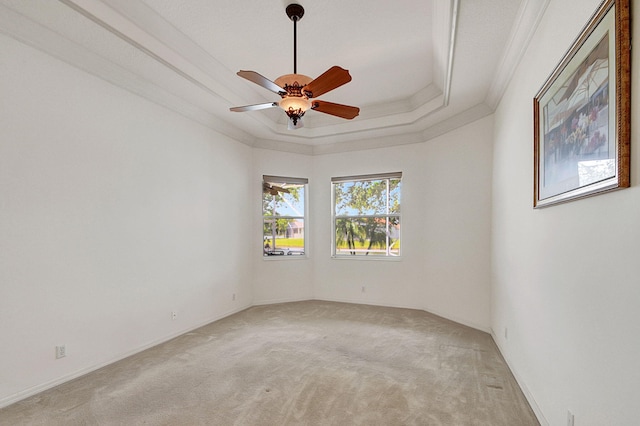 carpeted spare room with ornamental molding, ceiling fan, and a raised ceiling