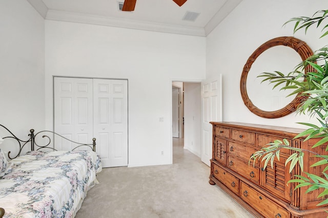 carpeted bedroom featuring crown molding, a closet, ceiling fan, and a high ceiling