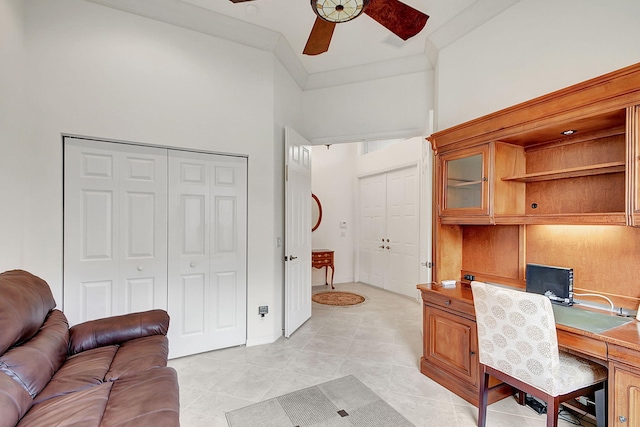 tiled home office featuring ceiling fan and a towering ceiling