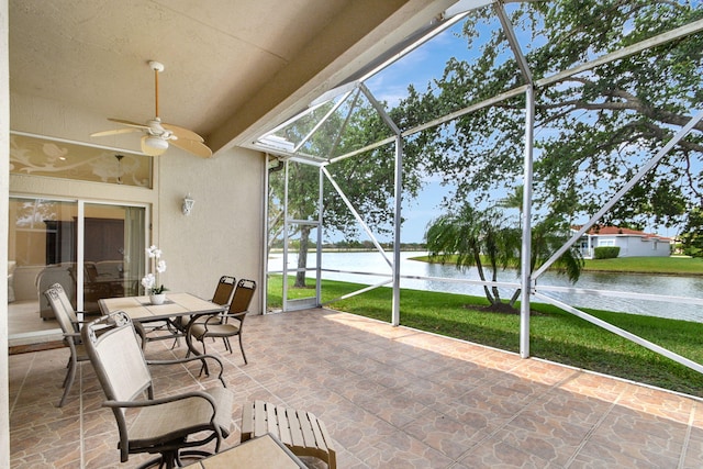 sunroom with ceiling fan and a water view