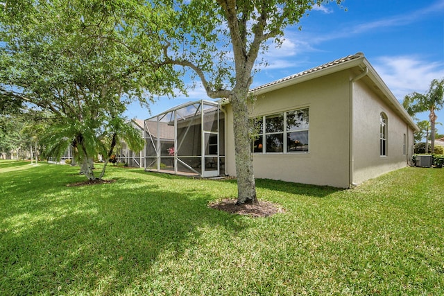 rear view of property with central AC unit, a lanai, and a lawn