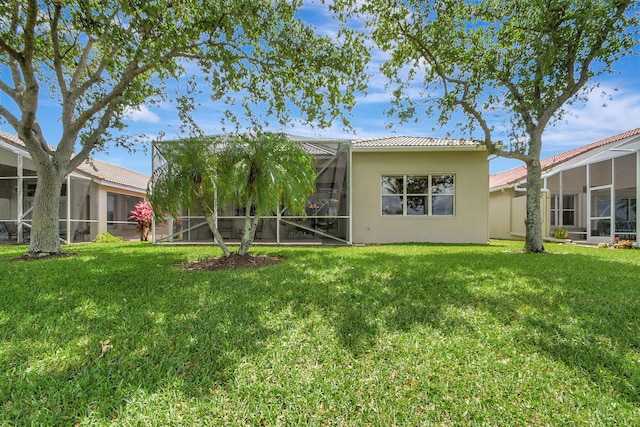 back of property featuring a lanai and a lawn